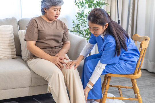Caregiver nurse assist elderly senior patient with knee pain during home physiotherapy session, provide medical care, physical support, exercise guidance recovery to improve joint mobility balance