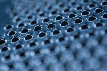 Macro closeup of perforated metal surface with triangular holes.