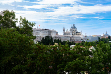 Fototapeta premium Wide panoramic view of the Royal Palace and Almudena Cathedral in Madrid Spain, showcasing European architecture with trees in foreground and daylight sky highlighting heritage and city landmarks