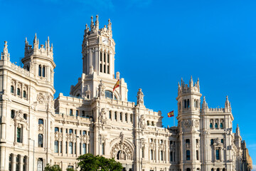 Panoramic view of Cibeles Palace in Madrid, Spain, ornate neoclassical towers and intricate facades under a blue sky. This landmark civic building is home to the city hall and cultural exhibitions.
