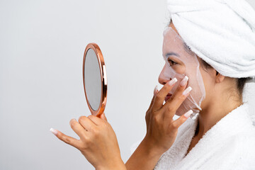 Young woman applying purifying facial sheet mask