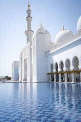 Vertical shot of beautiful white mosque with water in foreground, United Arab Emirates