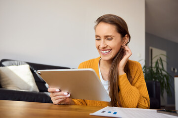 Happy woman at home using digital tablet