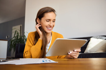Smiling woman at home using digital tablet