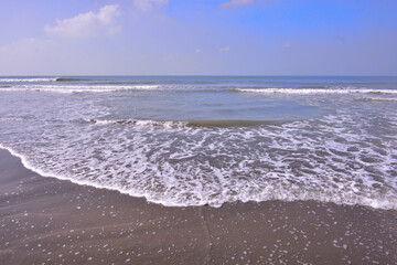 Expansive seascape of Cox's Bazar beach on the Bay of Bengal in Bangladesh, with a vast blue sky and gentle waves.