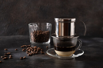 Vietnamese drip filter for coffee of stainless steel on black background. Traditional metal coffee maker for office, home and travel. Close up.