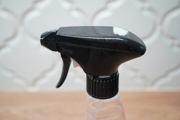Close-up of a black spray bottle nozzle, highlighting its trigger and design against a blurred backdrop