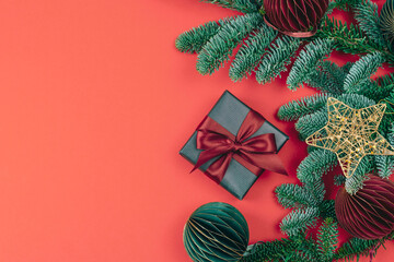 Christmas composition with gift box, fir branches and golden star on red background. Top view, flat lay, copy space