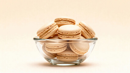 A bowl of macarons sits on a table. The macarons are all different colors and sizes