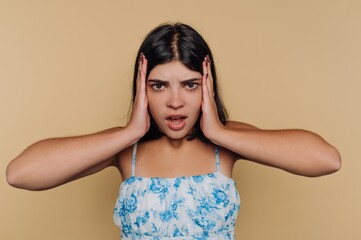 Fototapeta premium Young woman in floral dress holding her head in frustration.
