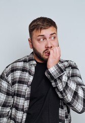 Obraz premium Man in plaid shirt biting nails, looking anxious