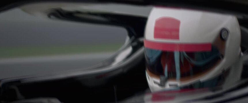 Close-up of a race car driver in a driving fast on a racing track, evening race