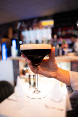 Hand Holding Espresso Martini in a Bar