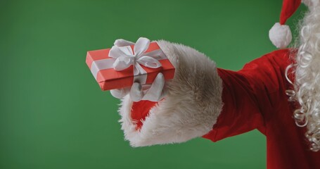 Santa Claus in a red suit with a white fur cuff and glove holding a gift box against a green background. Perfect for Christmas banners, cards, and holiday advertising.