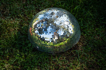 Disco ball in grass reflecting sunlight, creative minimal concept
