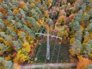 High voltage power lines through colorful autumn forest – aerial view