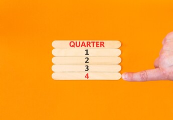 4th fourth quarter 4 symbol. Concept word Quarter 4 on beautiful wooden sticks. Beautiful orange background. Businessman's hand. Business, happy 4th fourth quarter 4 Q4 concept. Copy space.