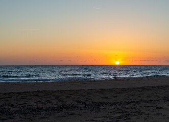 Obraz premium Peaceful sunset over calm sea and sandy beach in Crete