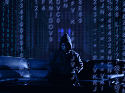 Hacker, coding and malware concept. Hooded computer hacker in cybersecurity on server room background, metaverse digital world technology.