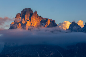 sunset on Alpe di Siusi in the Italian Dolomites - the sun shines through the clouds on a rocky alpine peak