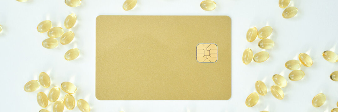 Gold credit card with emv chip surrounded by gel capsules on white background. - Powered by Adobe