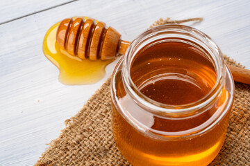 Honey jar and  honey dipper  on white wooden background
