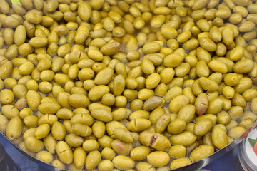 Fresh green olives piled in brine closeup