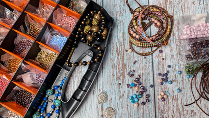Plastic bead box with colorful beads and bracelets on the wooden table. 