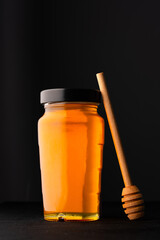 Honey jar and honey dipper on black background	