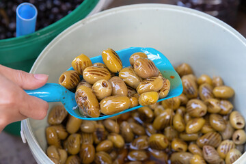 Cracked green olives being served with scoop