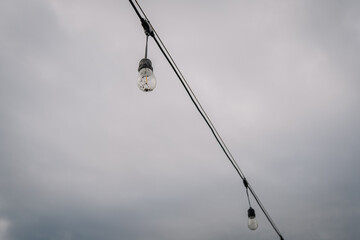 Decorative string lights hanging against a moody sky, creating a warm ambiance for outdoor gatherings and enhancing evening atmosphere