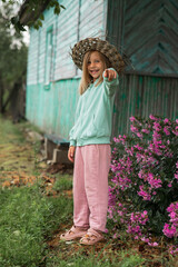 a girl is standing near a wooden house, waving her hand and laughing