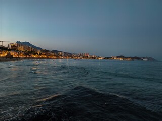 calm bay with city reflections, tranquil dusk by bay with mountain silhouette and glowing