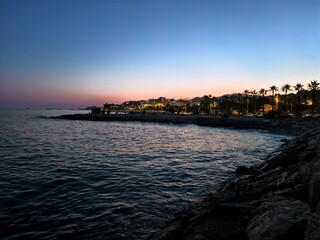Fototapeta premium vivid waterfront scene illuminated with colorful lights during peaceful blue hour with vibrant