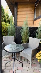A cozy terrace with wicker chairs near the wooden facade is the perfect place for relaxation, privacy, and inspiration in exterior design.