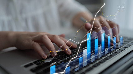 A business professional engages with financial data on a laptop. The image shows charts and graphs illustrating growth trends in a modern workspace. Scalp