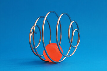 Finding a way out of a problem. An orange ball trapped inside a metal spiral that forms a sphere