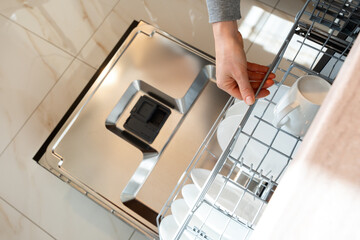 Dishwasher machine. Top view of loading dishwasher rack with plates.
