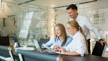 Team collaborating on project in modern office space with laptops and charts