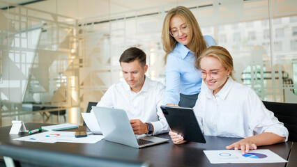 Fototapeta premium Team collaboration in a modern office space with digital devices and charts