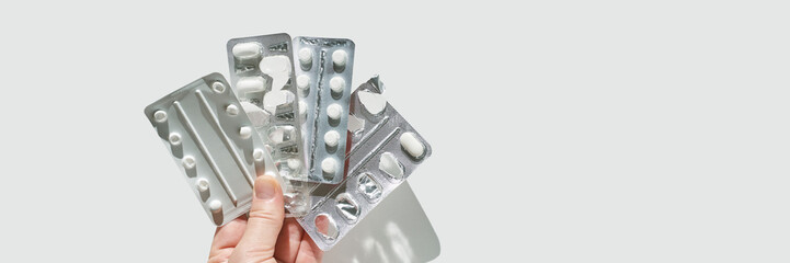 Hand holding blister packs of pills on white background for medical and pharmaceutical concepts.