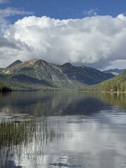 A pristine lake mirrors the majestic mountains above, creating a serene and tranquil landscape