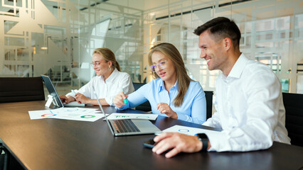 Team collaborating on a project in a modern office space with laptops and documents