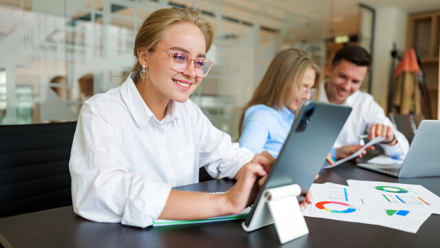 Team members collaborating on a project in a modern office space with digital devices - Powered by Adobe