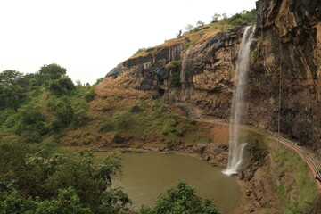 October 23, 2025; Ellora Caves, Maharashtra, India: A wide view shows a waterfall cascading into a plunge pool with a walkway behind it at this UNESCO Heritage site.