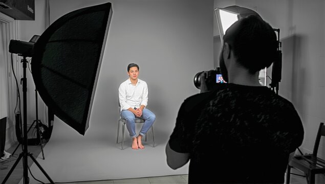 Young Man Sitting for a Photoshoot in a Studio With Soft Lighting and a Neutral Backdrop - Powered by Adobe
