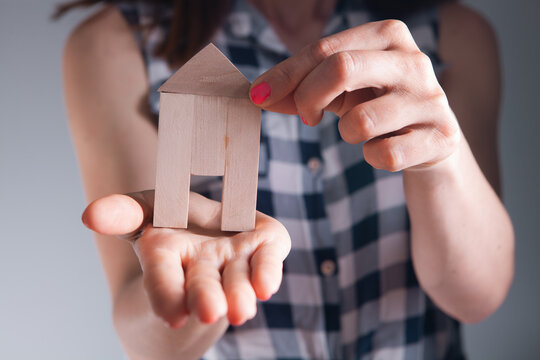 woman hand with wooden house model