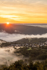 Warm sunrise over the Rhine River near Bad Salzig, Germany, illuminating misty valleys and lush scenery