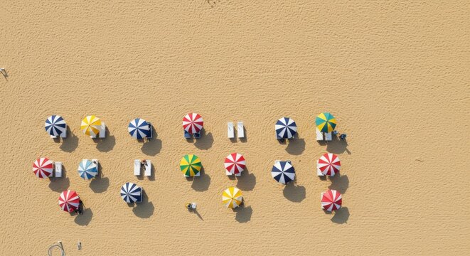 Aerial top down view of colorful beach umbrellas on sand. Summer vacation and travel background with minimalist pattern and copy space