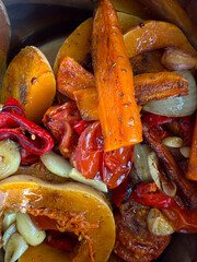 Roasted vegetables with pumpkin, carrot, pepper and garlic. Homemade healthy meal, colorful ingredients and rustic cooking emphasizing texture and natural flavor.